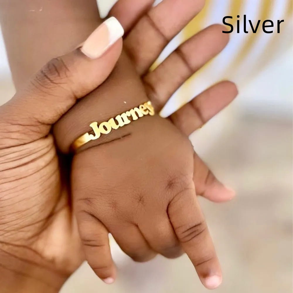Gold name ring on baby’s hand with Personalised Stainless Steel Alphabet Titanium Bracelet.