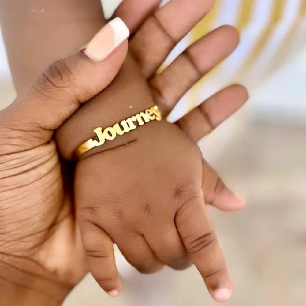 Gold name bracelet on a baby’s wrist with Personalised Stainless Steel Alphabet design.
