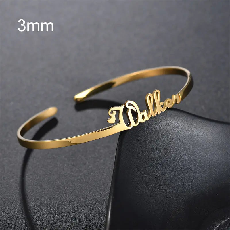Goldfarbenes Edelstahlarmband mit personalisiertem Namensdesign.