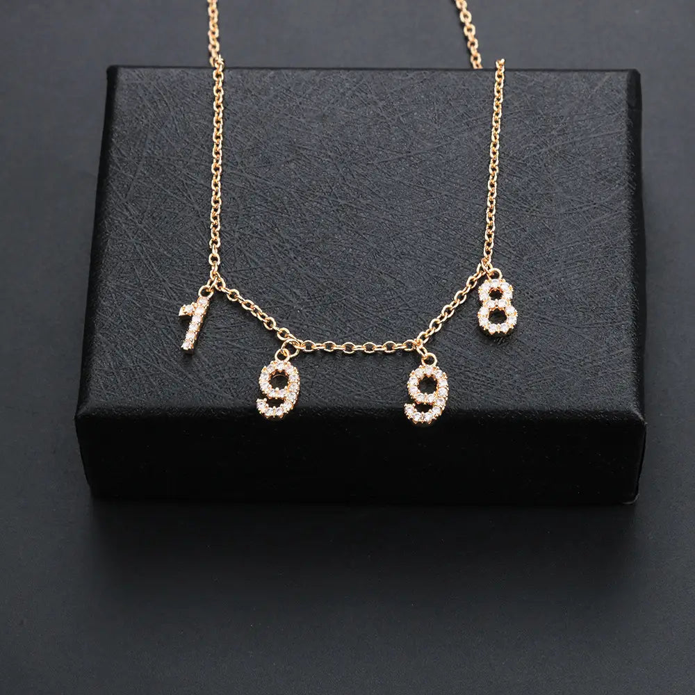 Gold zircon letter necklace featuring diamond-studded angel and rhinestone number pendants.